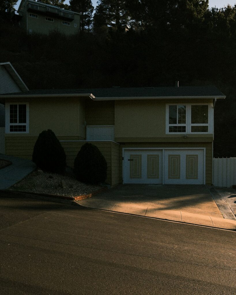 Real photograph of a suburban house with front lawn, garage and driveway