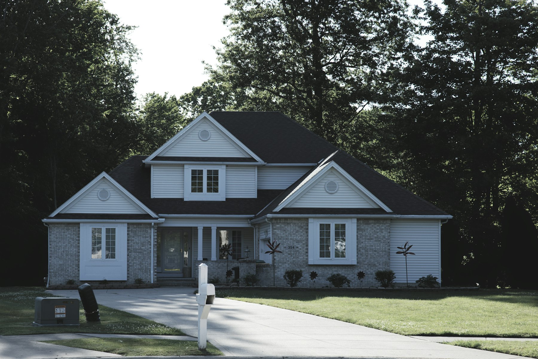 Real photograph of a suburban home with lawn and trees, representing residential site-plan projects